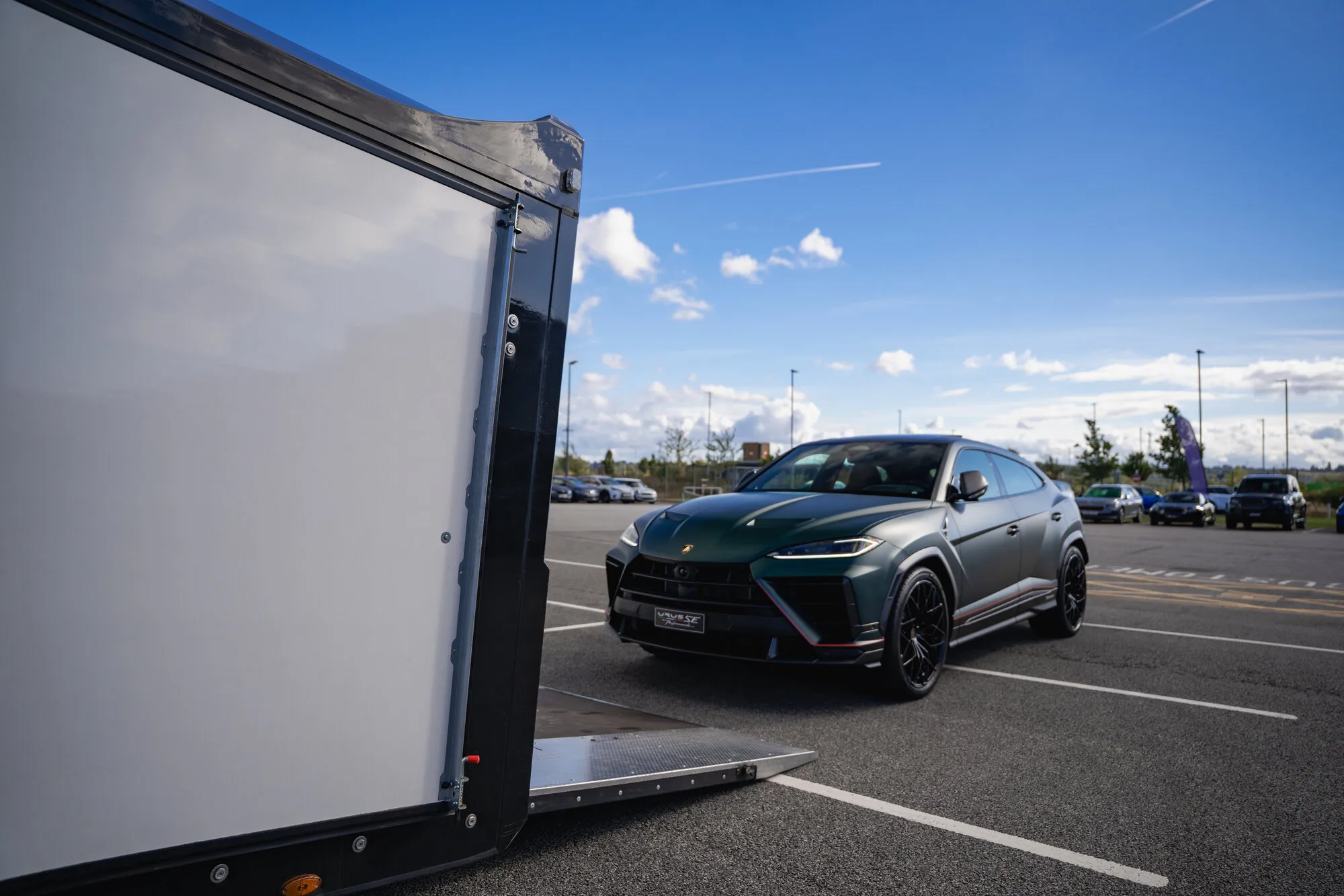 A Lamborghini Urus SE beside the Huntsmiths enclosed trailer, ramp down